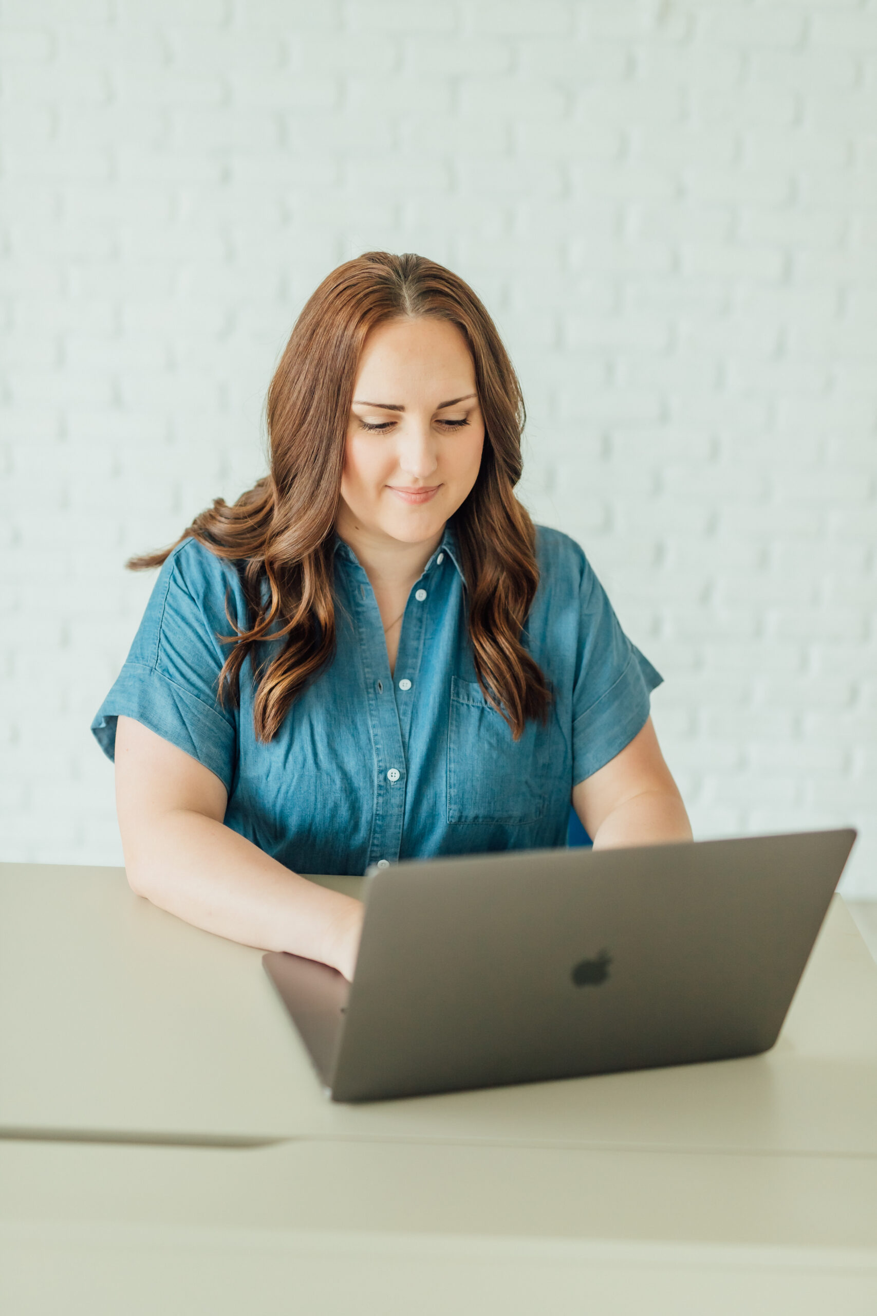 Ashlee Wiggins sitting at a desk and working on her laptop