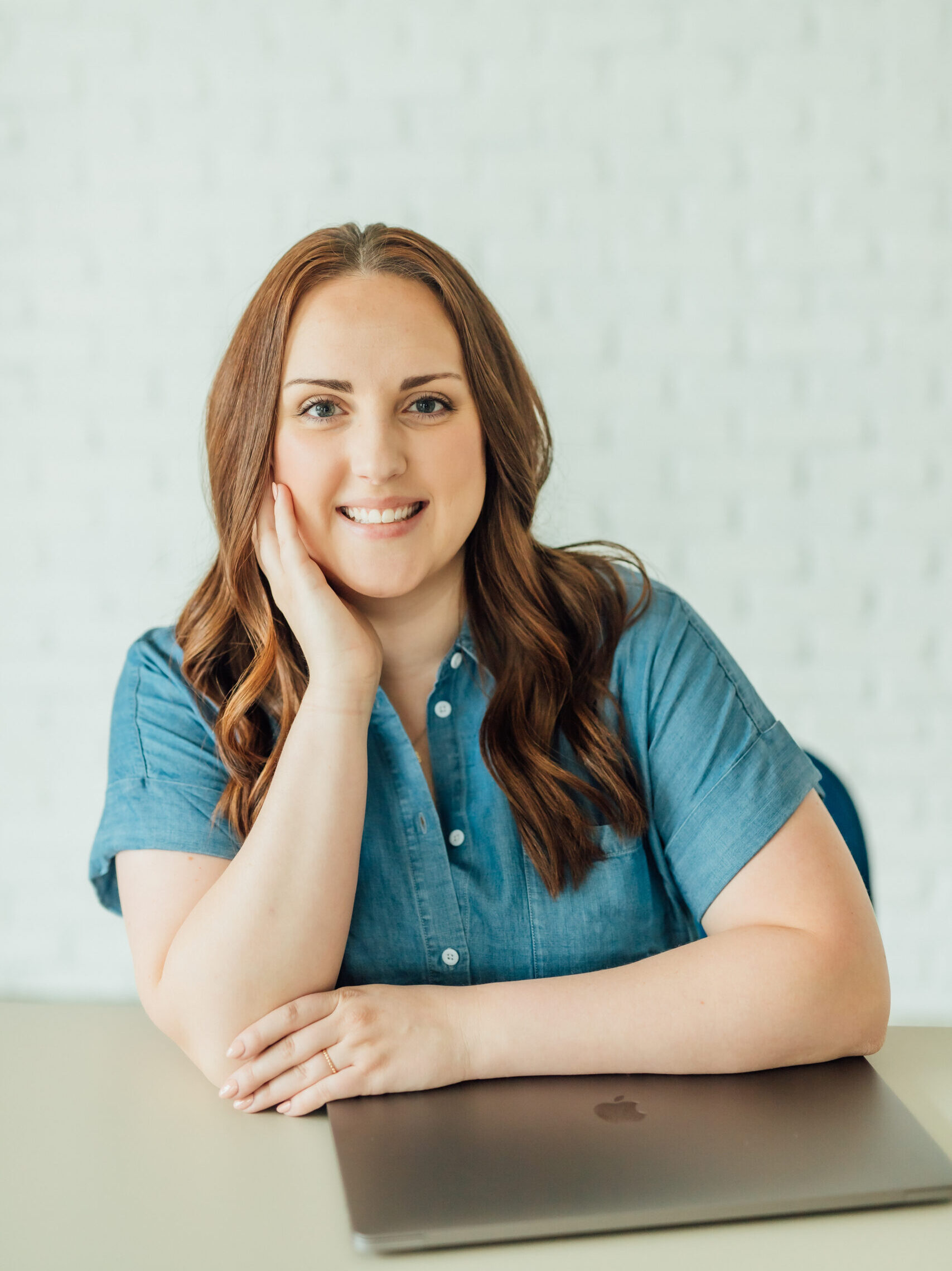 Ashlee Wiggins sitting at a desk with her laptop and smiling