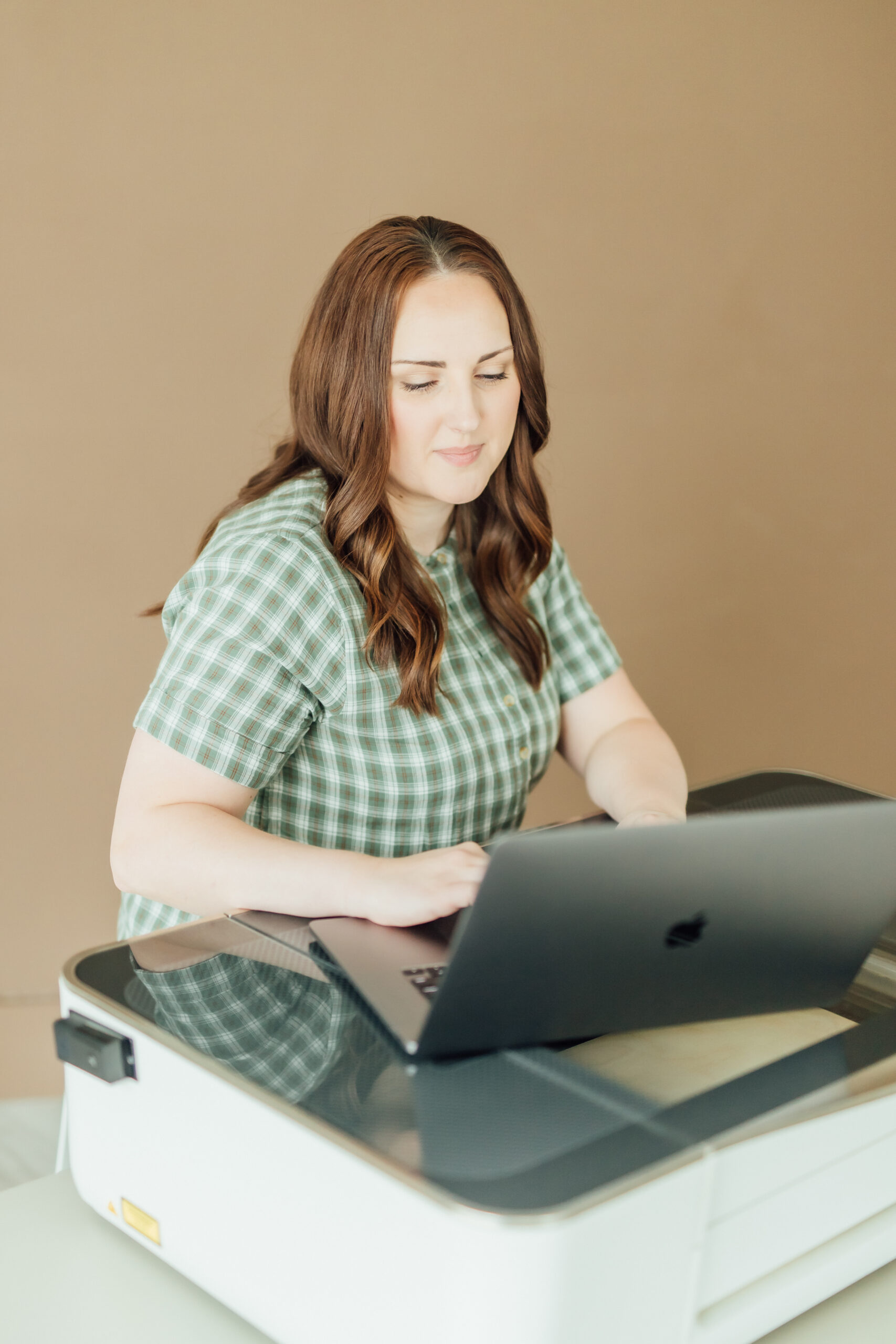 Ashlee Wiggins sitting at her laser with a laptop on top and working