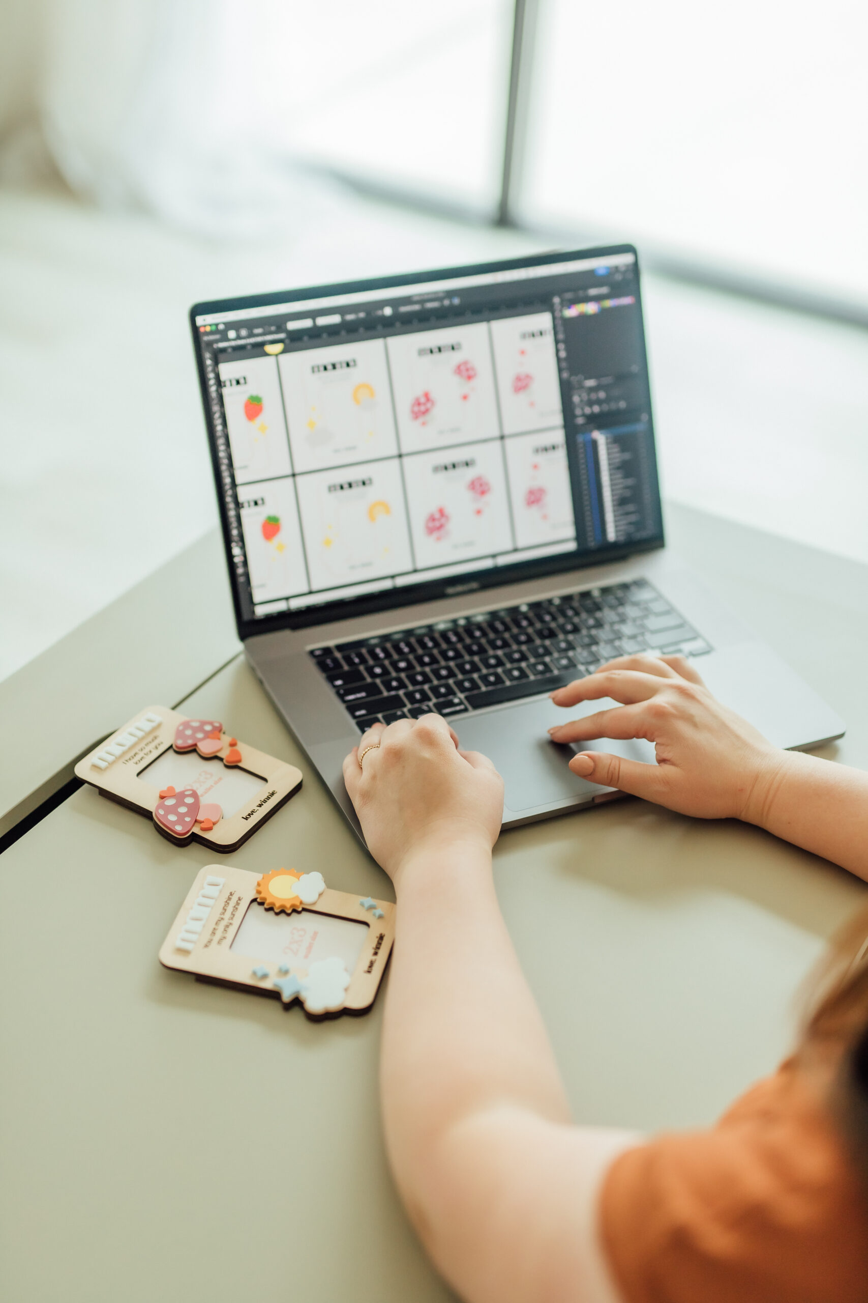 Ashlee Wiggins designing laser SVG files at a desk with laser cut products next to her