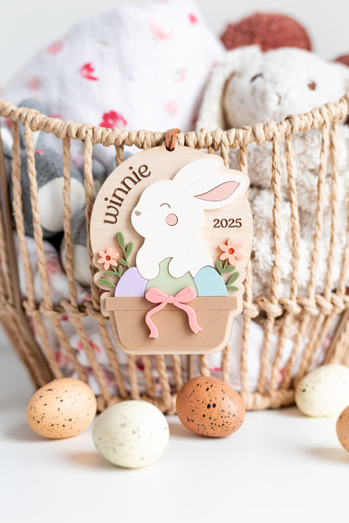 Laser cut wooden Easter tag featuring 3D elements of a bunny in a basket with eggs and florals and a child's name engraved by Made of Embers